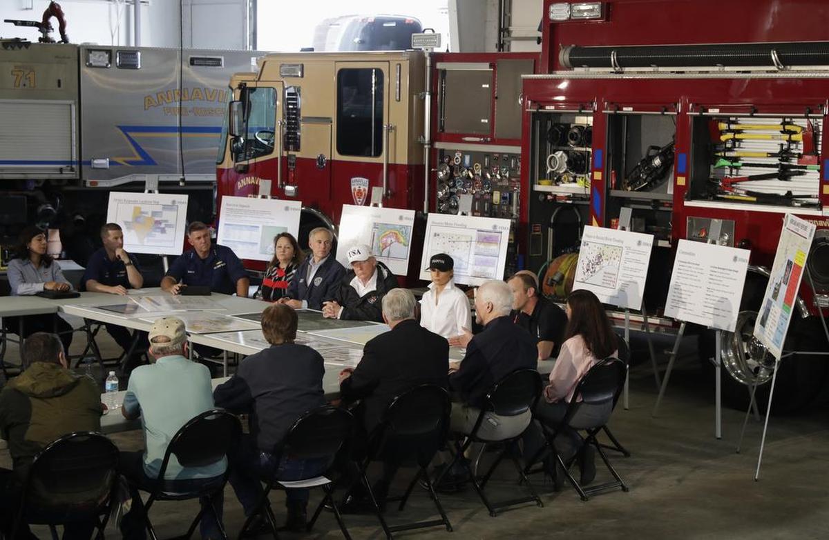 El presidente de Estados Unidos, Donald Trump, acompañado por el gobernador de Texas, Greg Abbott, y la primera dama, Melania Trump, escucha durante una reunión informativa sobre los esfuerzos de ayuda de Harvey el martes 29 de agosto de 2017 en el Firehouse 5 de Corpus Christi, Texas.