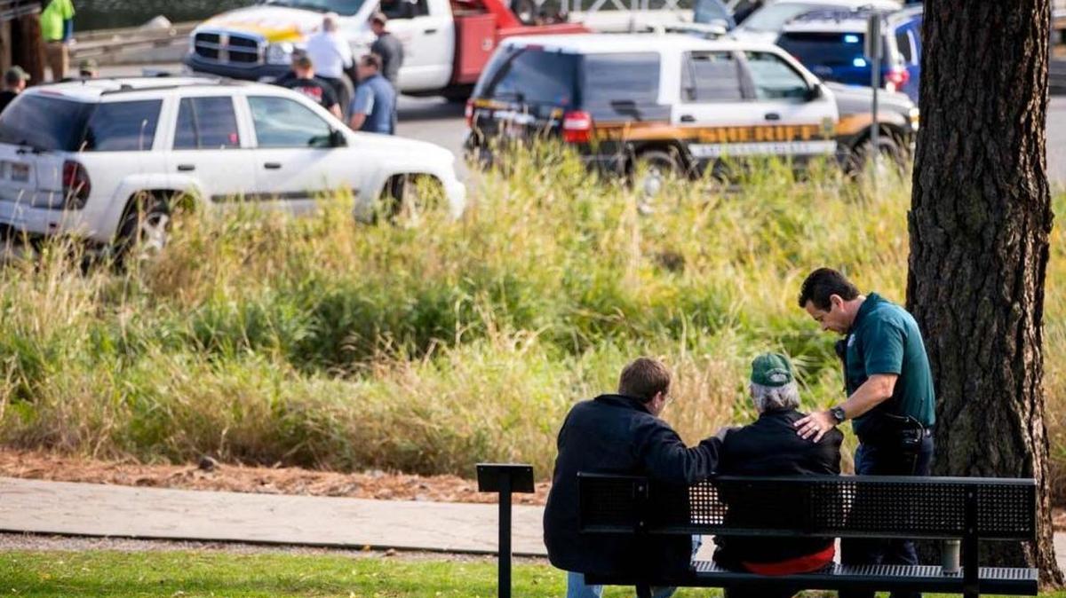 Policías consuelan a la persona que encontró el auto hundido con los cuerpos de Misty Phelps y sus dos hijos, Riley y Tristan, en el lago Fernan, cerca de Coeur d’Alene. El caso está bajo investigación.