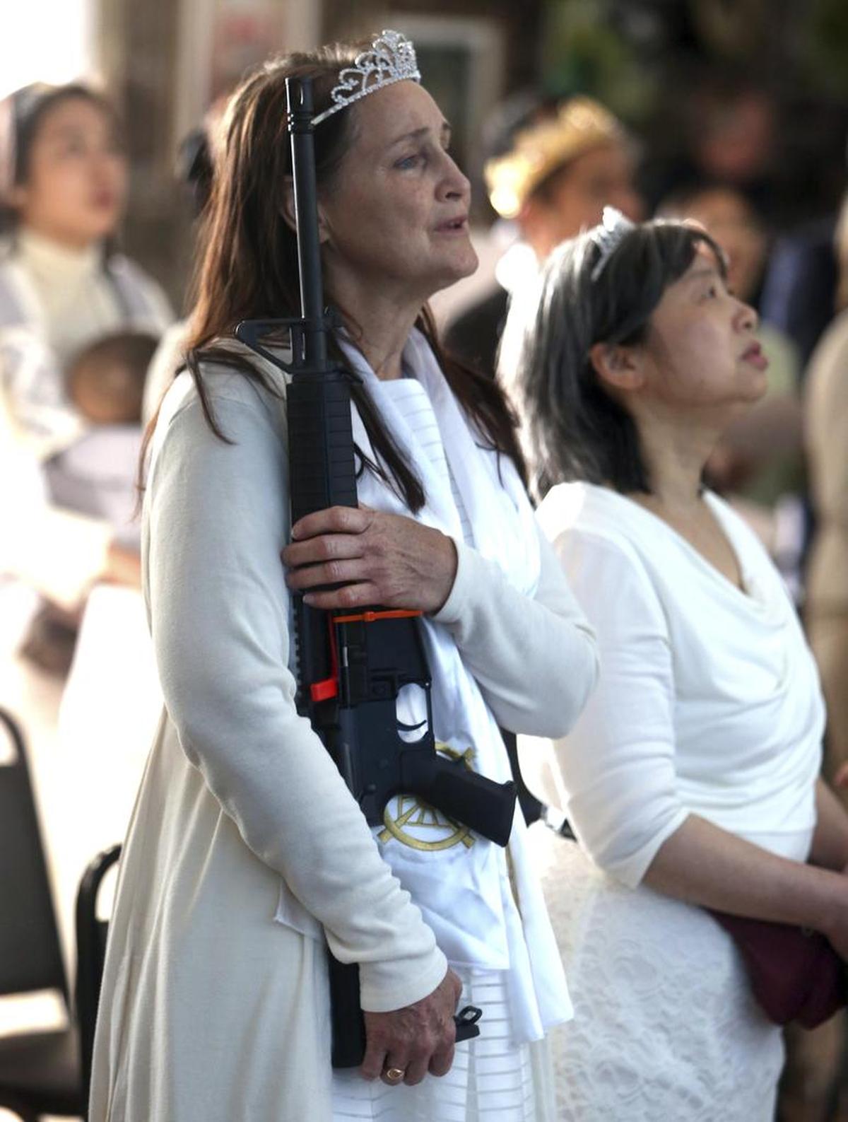 Una mujer canta el himno nacional mientras carga su fusil en la ceremonia del miércoles en World Peace and Unification Sanctuary, en Newfoundland, Pennsylvania.