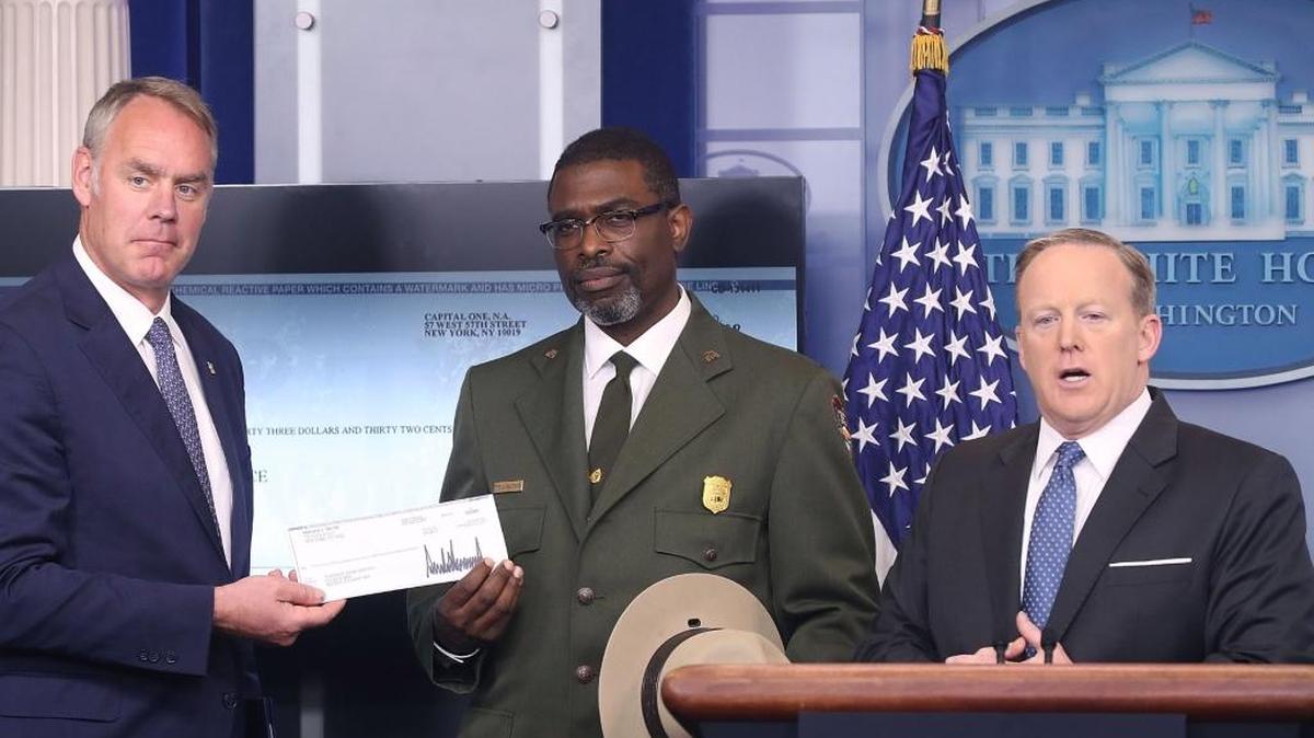 El secretario de prensa de la Casa Blanca, Sean Spicer (der.), le entrega al secretario de Interior, Ryan Zinke (izq.), el cheque con el primer trimestre del sueldo del presidente Donald Trump que donó al Servicio de Parques Nacionales. Tyrone Brandyburg (centro), superintendente de Harpers Ferry National Historical Park recibe el cheque el 3 de abril en la Casa Blanca.
