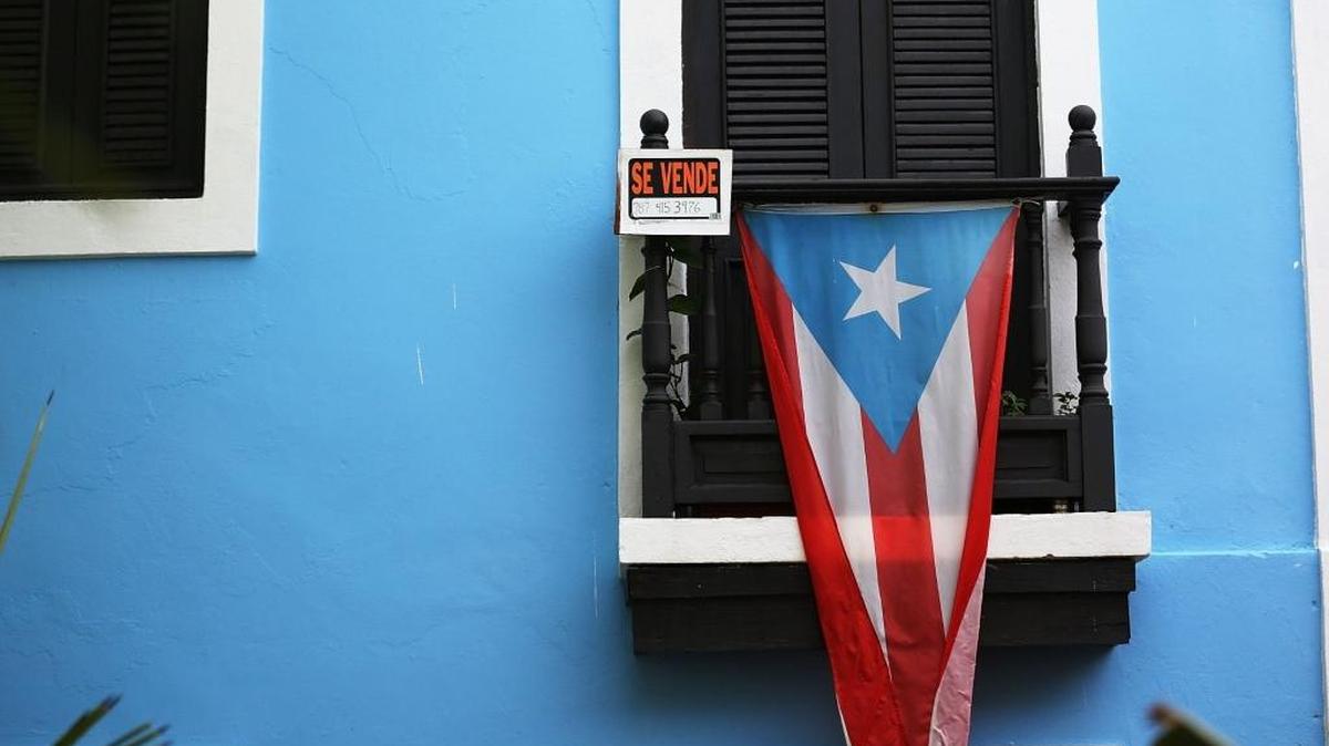 Un anuncio de venta se despliega en el balcón de una propiedad en San Juan. A medida que la situación económica empeora, muchos abandonan la isla.