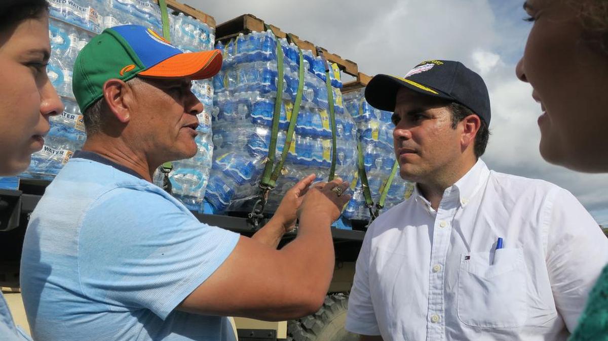 Fotografía del 5 de octubre de 2017, que muestra al gobernador de Puerto Rico, Ricardo Rosselló (d), escuchando al alcalde del municipio Barranquitas, Francisco "Paco" López (i), junto a su suministro de botellas de agua para la población en el municipio Barranquitas (Puerto Rico).