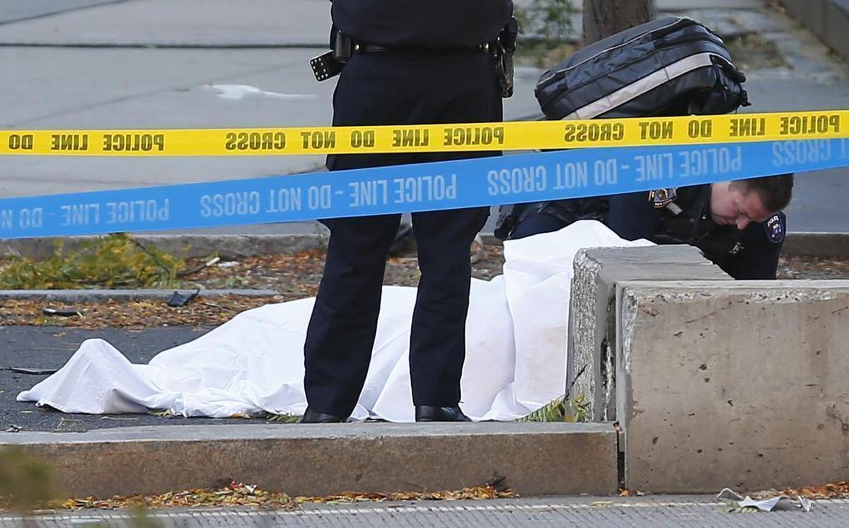 Un paramédico observa un cuerpo cubierto por una sábana blanca en un carril de bicicletas, el martes 31 de octubre de 2017 en Nueva York. Un automovilista condujo atropelló a varias personas cerca del monumento al World Trade Center, dijeron la policía y testigos.