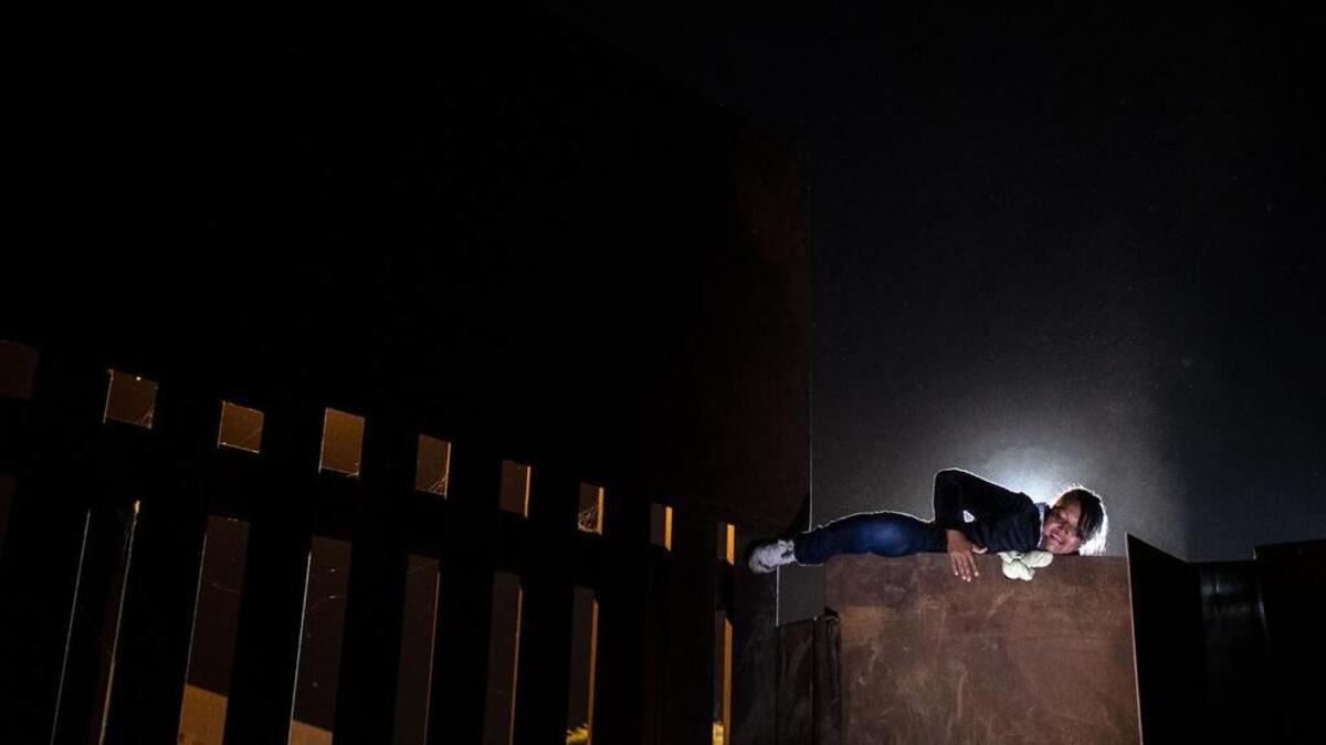 Una mujer sube la barrera de metal que separa a México y los Estados Unidos para cruzar de Playas de Tijuana en México a los Estados Unidos, el 3 de diciembre de 2018.