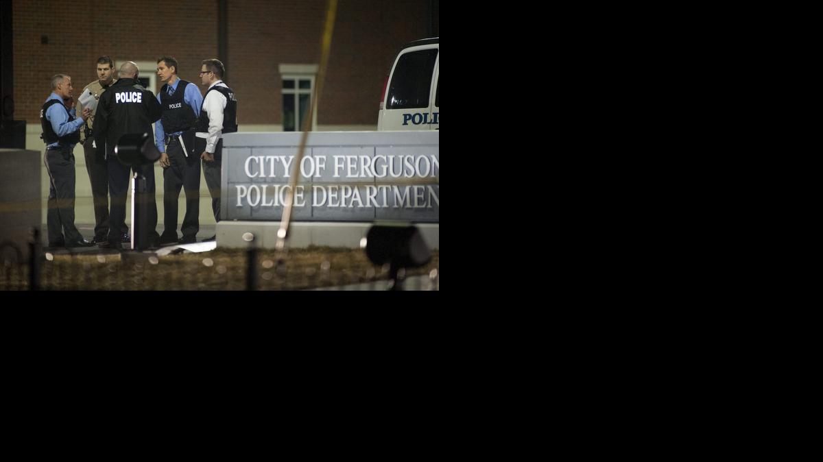 <cutline_leadin>Varios investigadores</cutline_leadin> buscan evidencias a las puertas del Departamento de Policía de Ferguson, Missouri en la madrugada del jueves, después del tiroteo registrado en ese lugar y que dejó a dos agentes heridos.