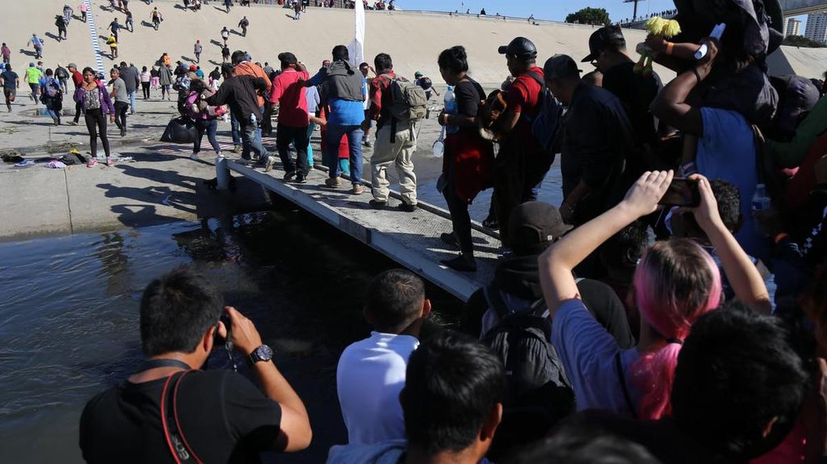 Un grupo de personas tratan de cruzar el domingo 25 de noviembre, la garita El Chaparral, de la ciudad de Tijuana, en el estado de Baja California (México).