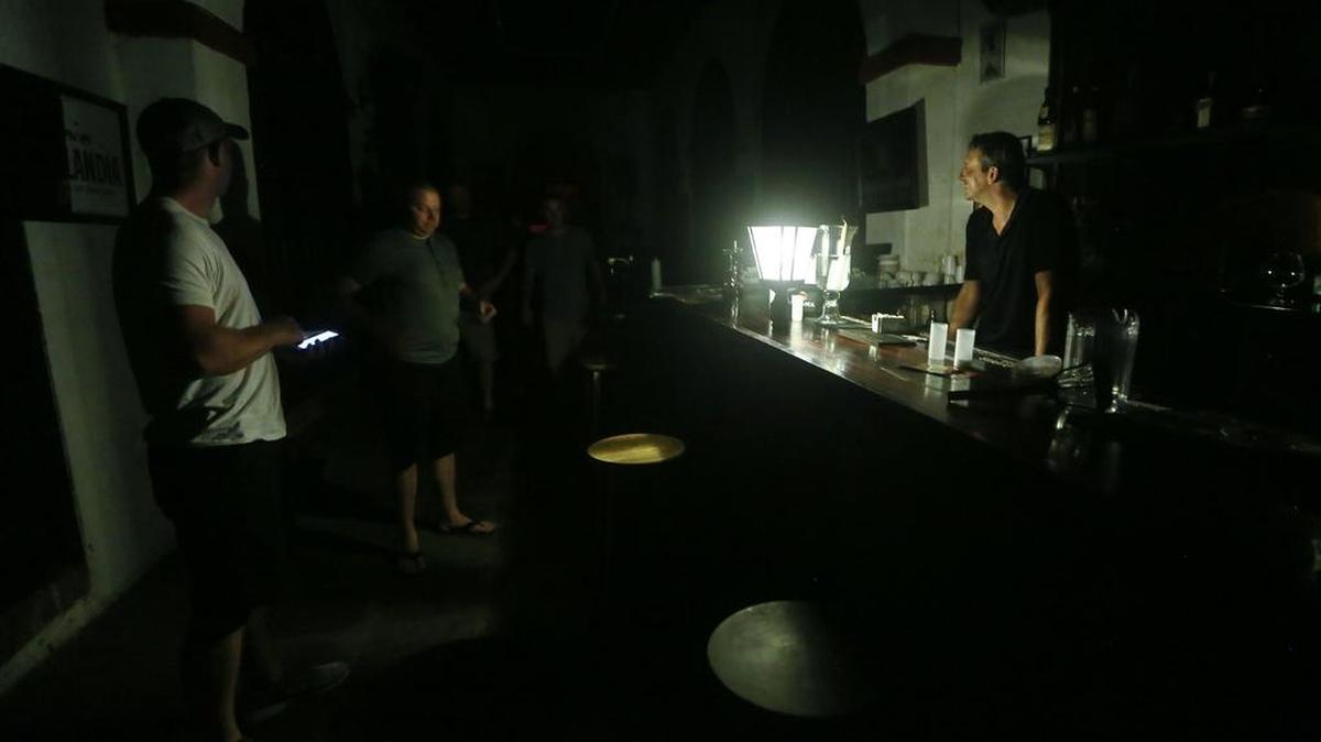 Un barman saluda a los clientes con una lámpara solar solitaria, en un bar sin electricidad, en el turístico barrio del Viejo San Juan, el 13 de octubre de 2017 en San Juan, Puerto Rico.