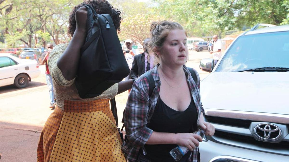 La estadounidense Martha O 'Donovan, derecha, se dirige a un tribunal escoltada por una oficial de policía vestida de civil, en Harare, Zimbabue.