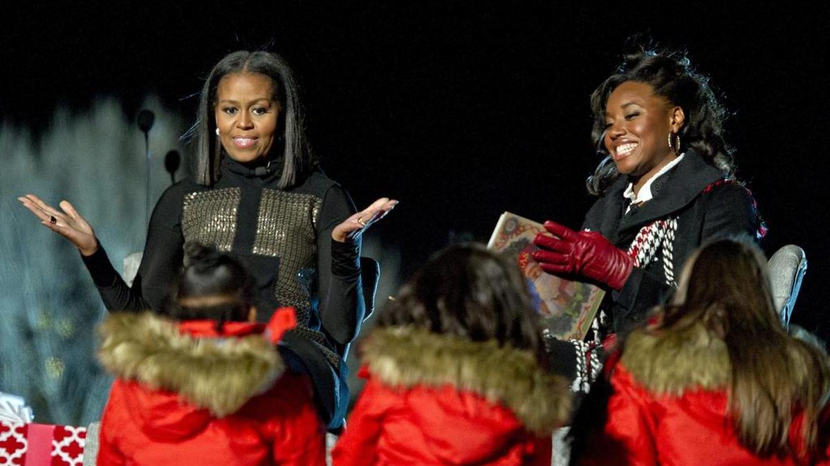La primera dama estadounidense, Michel Obama (i), y la medallista olímpica Simone Manuel (d) leen un cuento a un grupo de niños durante la ceremonia de encendido del árbol navideño en Ellipse, Washington (Estados Unidos), el de diciembre de 2016. EFE/Ron Sachs/Pool