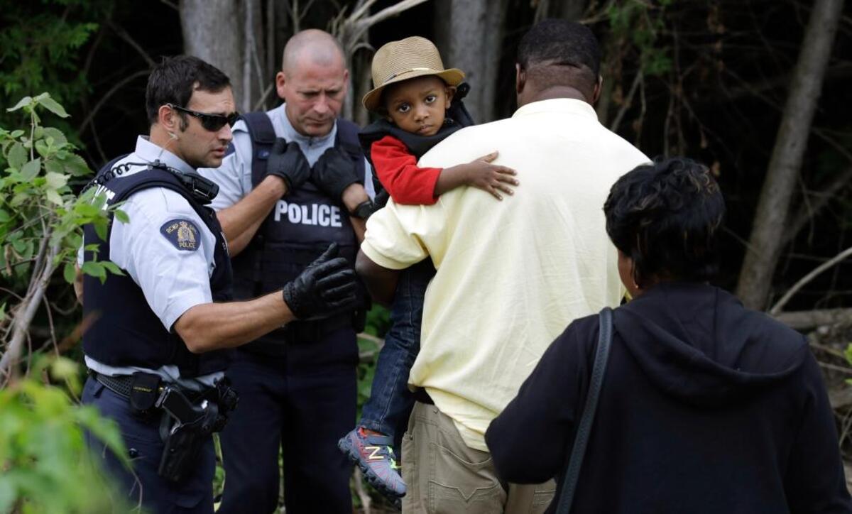 Un niño haitiano va en brazos de su padre al acercarse a un punto de cruce ilegal en la frontera con Canadá el 7 de agosto del 2017.