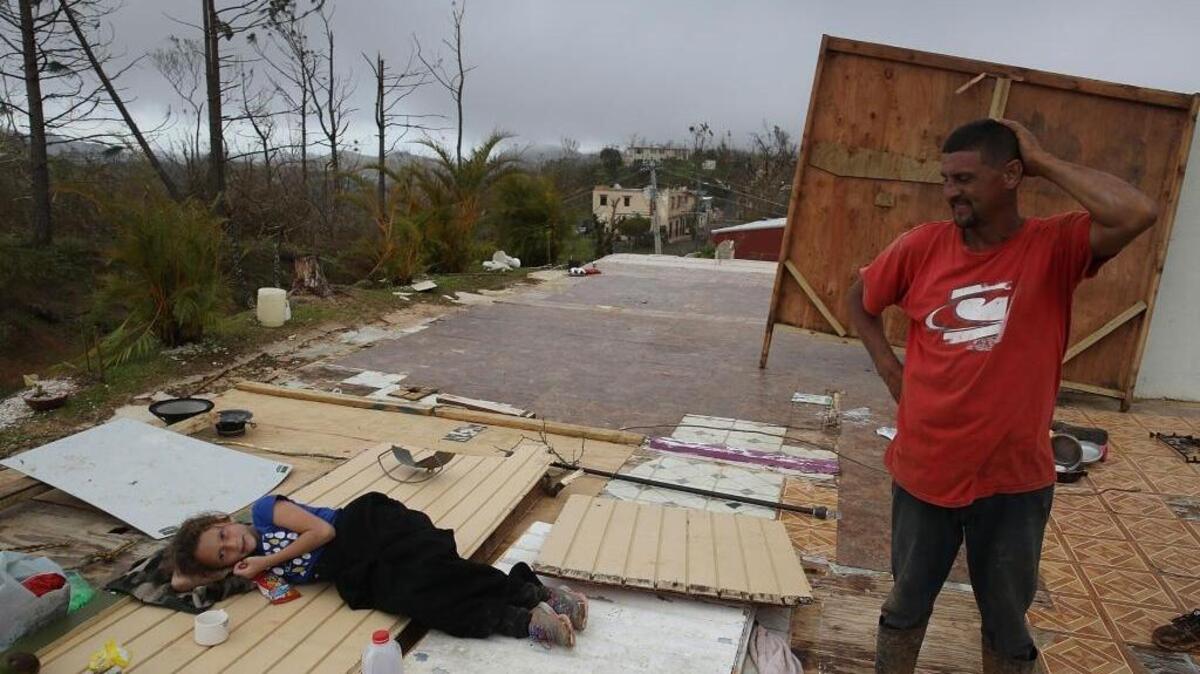 Karlian Mercado, de 7 años, sy su padre Carlos Flores observan lo que queda de su casa en Hayales de Coamo, Puerto Rico, el 24 de septiembre.