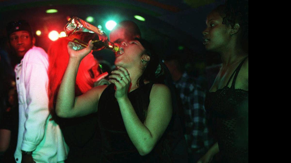 
Una joven toma alcohol directamente de una botella de tequila en una fiesta es esta foto de archivo.
