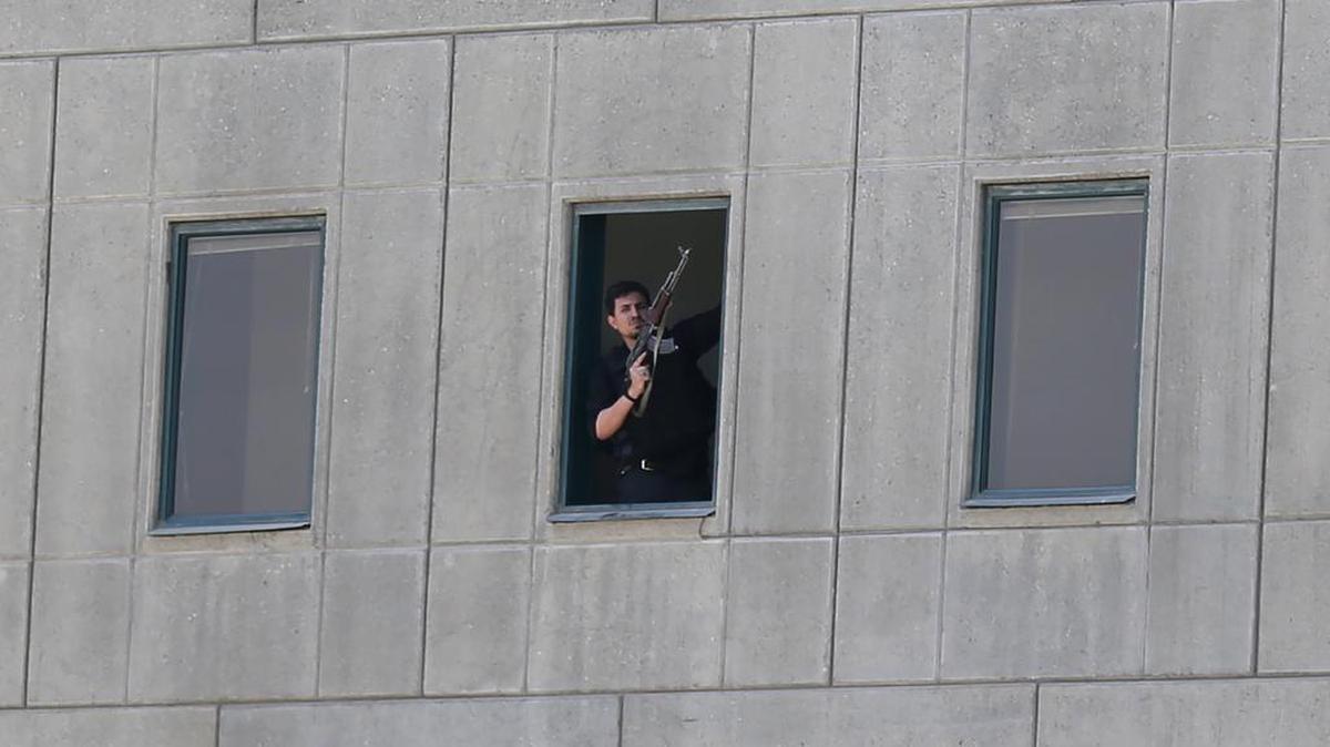 Un policía iraní sostiene un arma mientras está parado junto a una ventana en el parlamento iraní en la capital Teherán el 7 de junio de 2017 durante un ataque contra el complejo.