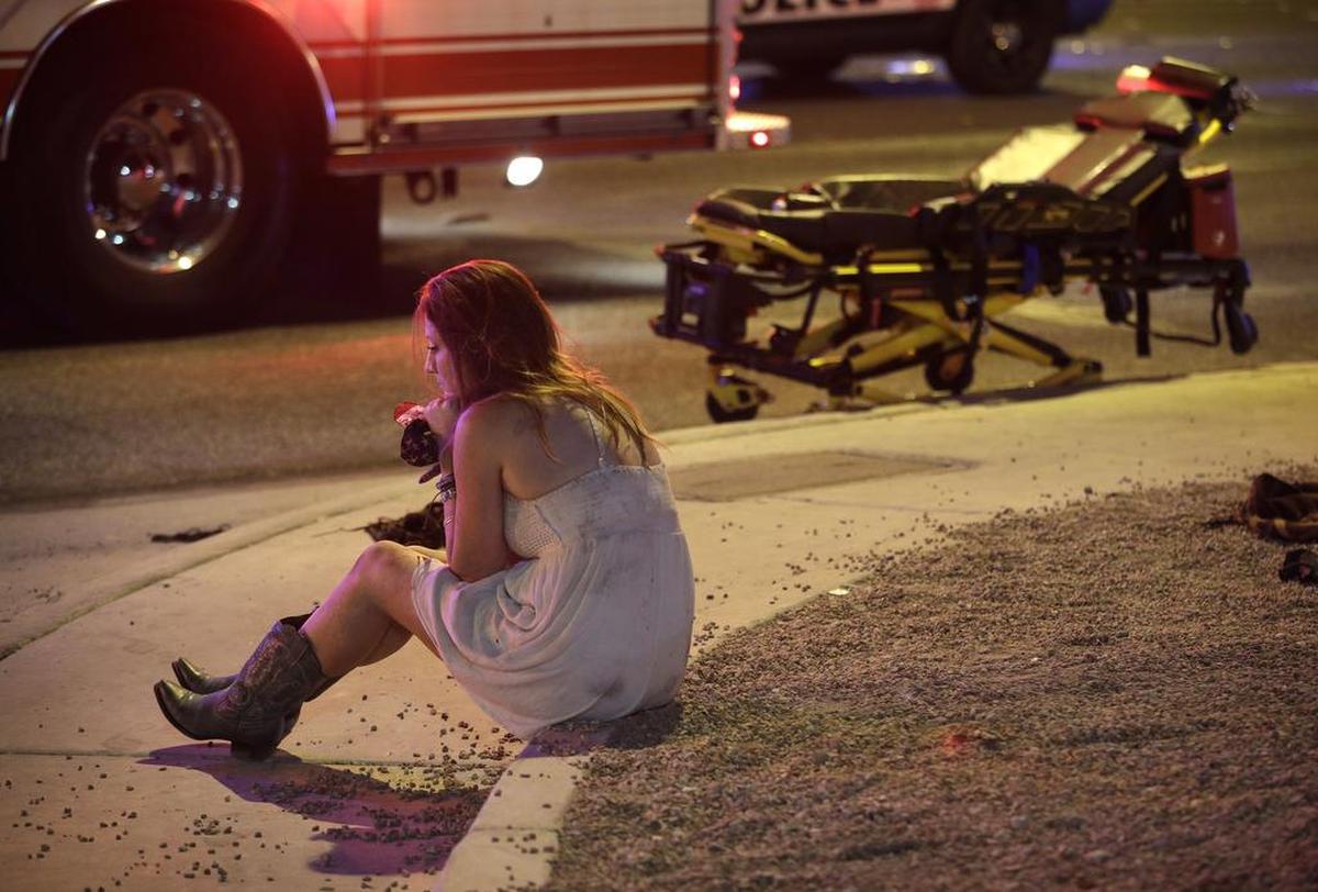 Una mujer sentada en una acera en la escena de un tiroteo fuera de un festival de música a lo largo del Strip de Las Vegas, el lunes 2 de octubre de 2017, en Las Vegas.