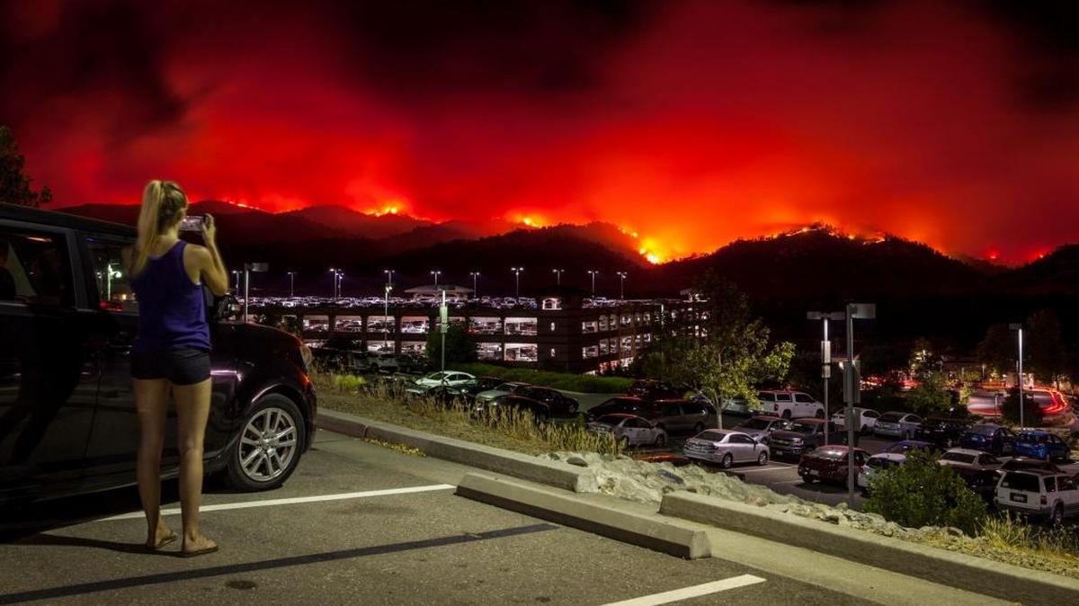 Una residente local toma fotografías del estacionamiento superior del Cache Creek Casino Resort mirando el incendio del condado, ya que se está quemando fuera de control en Brooks, California.