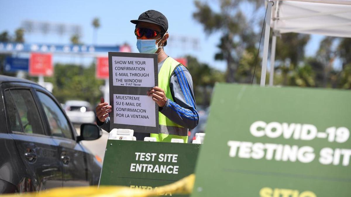 El personal designado dirige los autos en un sitio de prueba COVID-19, el 15 de julio de 2020 en el Dodgers Stadium en Los Ángeles, California.