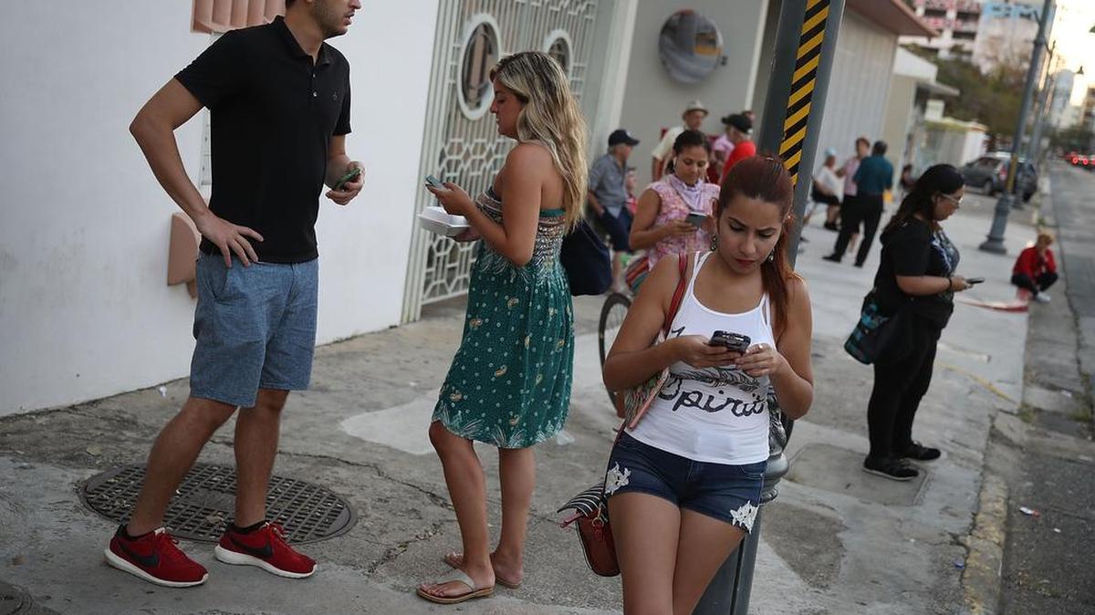 Varias personas en San Juan tratan de encontrar alguna señal wi-fi gratis para conectar su teléfono celular inutilizados después del paso del huracán María.