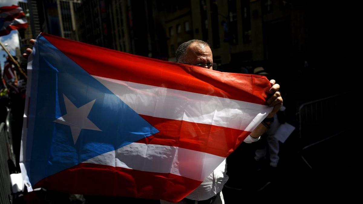 
Un hombre sujeta una bandera de Puerto Rico durante una manifestación en frente de las oficinas del financiero estadounidense John Paulson en Nueva York, Estados Unidos, hoy 13 de agosto de 2015. Los manifestantes están en contra de las inversiones de Paulson y de otros ejecutivos de fondos financieros realizadas en la isla, que acumula una deuda de 73.000 millones de dólares.
