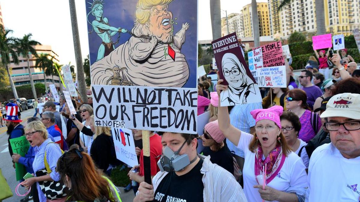 Manifestantes protestan con carteles el sábado 4 febrero de 2017, contra el presidente de Estados Unidos, Donald Trump, en West Palm Beach.
