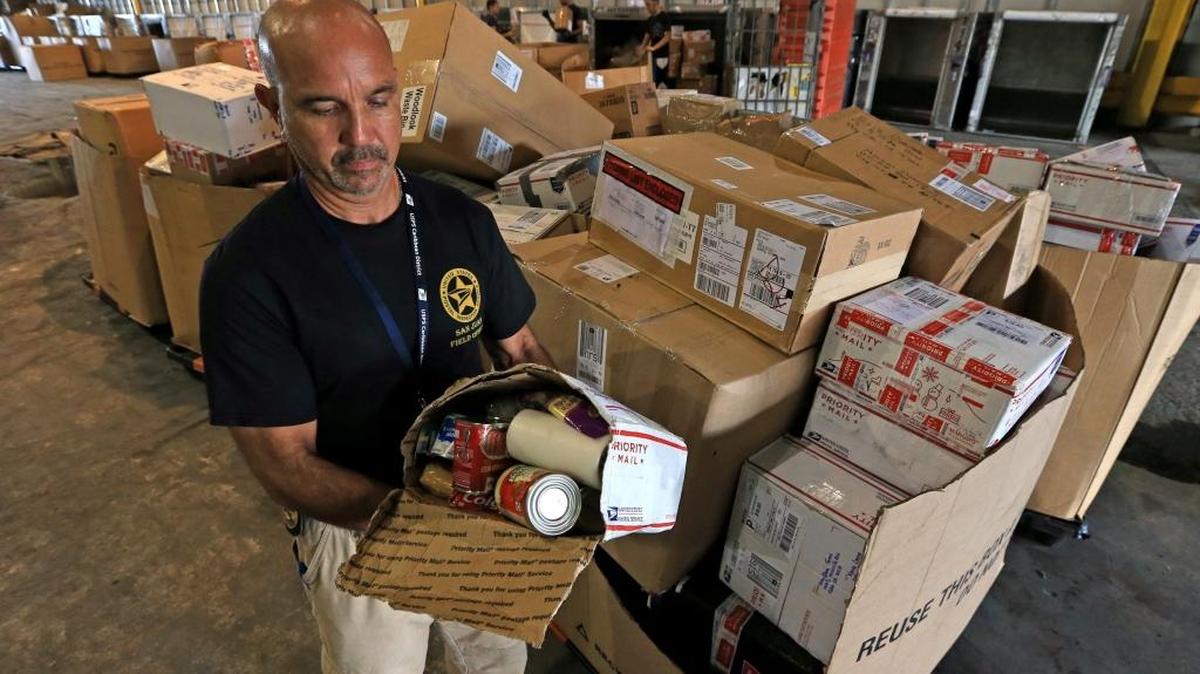 El inspector postal y agente federal Eliezar Julián levantó una caja que debía pesar solo 70 libras. Por una esquina rota del paquete se podía ver los artículos adentro en el área de carga del Aeropuerto San Juan Luis Muñoz Marín en Puerto Rico.