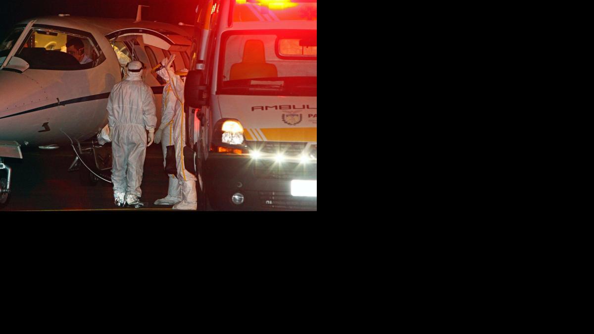 
Trabajadores del sector salud de Brasil permanecen al lado de un avión y de una ambulancia después de trasladar a un hombre con fiebre que había viajado a Africa.
