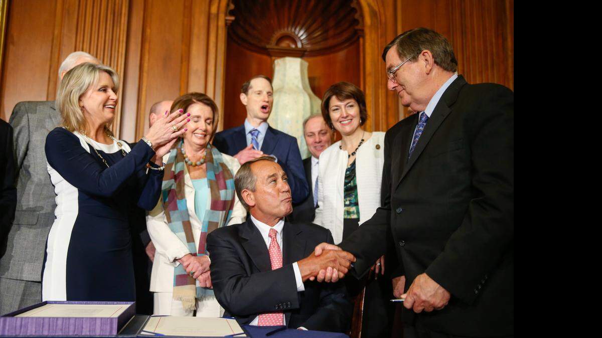 
El vocero de la Cámara de Representantes, John Boehner, estrecha la mano del representante Michael Burgess, luego de firmar una ley bipartidista para bloquear cortes al Medicare, en el Capitolio. 
