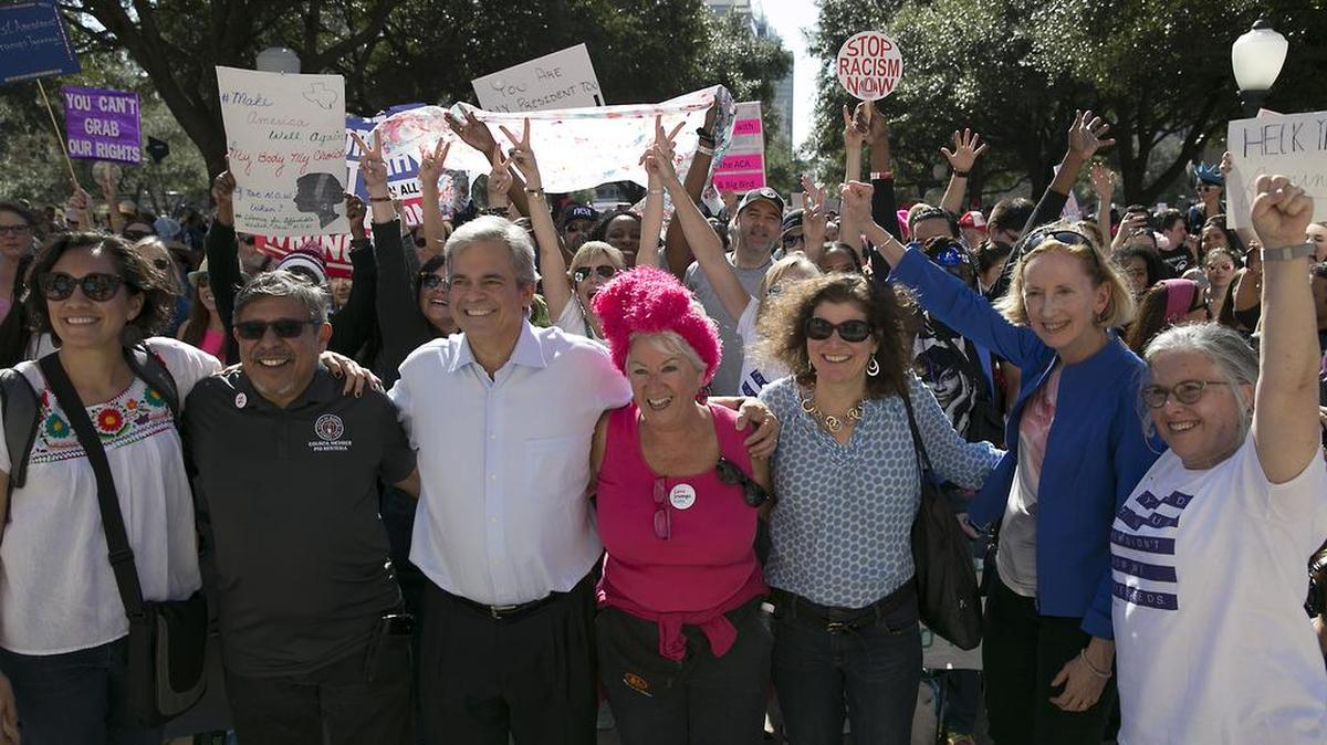 Steve Adler (centro, con camisa blanca), alcalde demócrata de Austin, Texas, y varios funcionarios locales participan en una marcha contra el presidente Donald Trump, en Austin el 21 de enero del 2017.