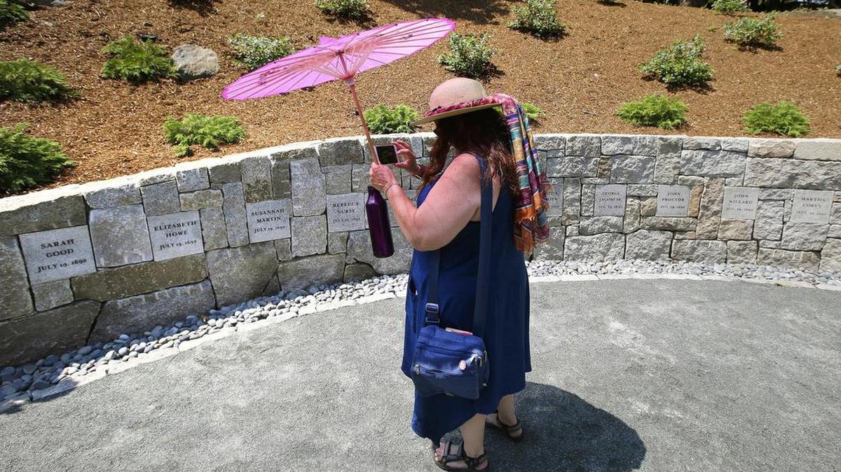 En fotografía del 19 de julio del 2017, una mujer graba un video de un monumento en Salem, Massachusetts, donde cinco mujeres fueron ahorcadas como brujas hacía 325 años.