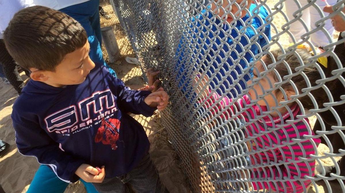 Docenas de familia se reunen en la frontera junto a la cerca que los separa entre Mexico y los Estados Unidos.