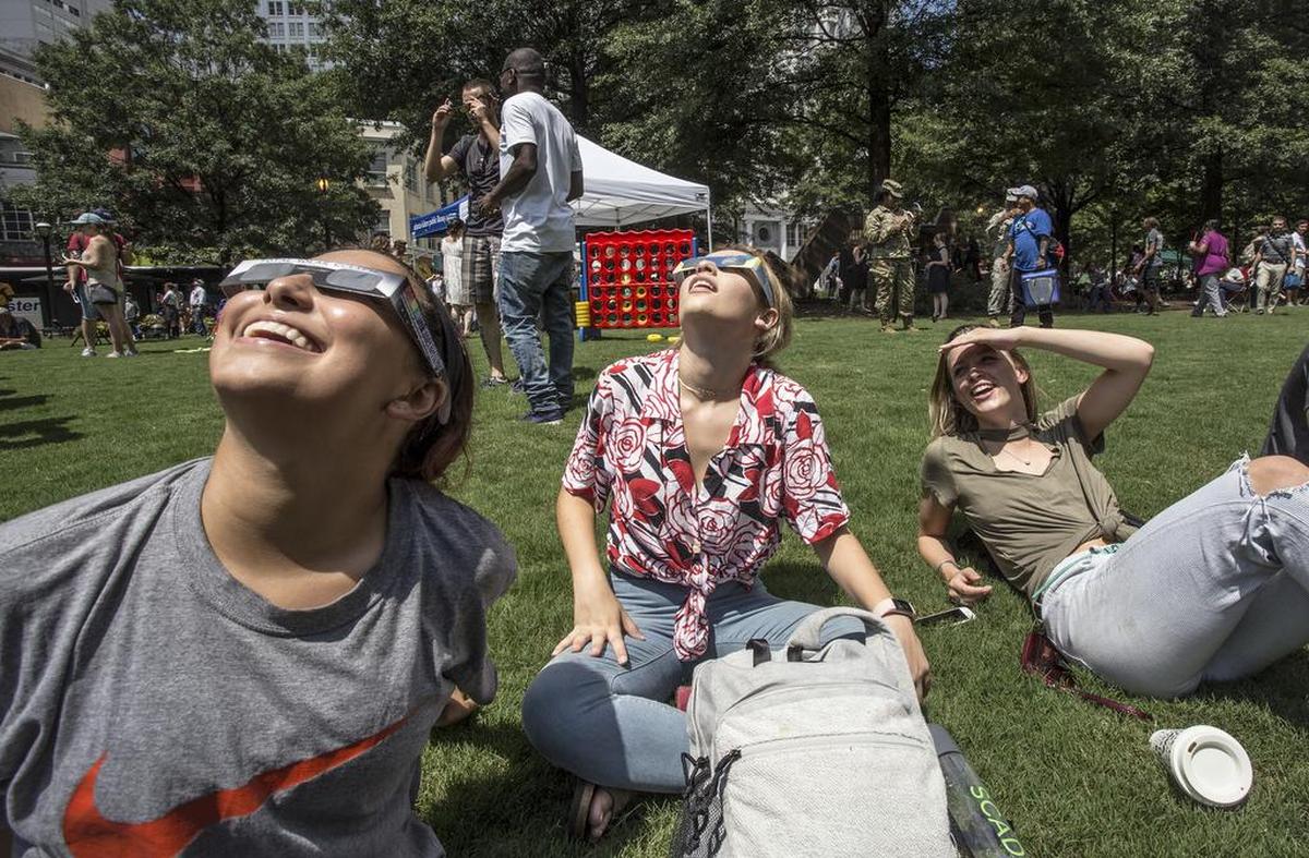 Tres mujeres en Woodruff Park ven el eclipse solar el lunes 21 de agosto de 2017, en Atlanta, Georgia.