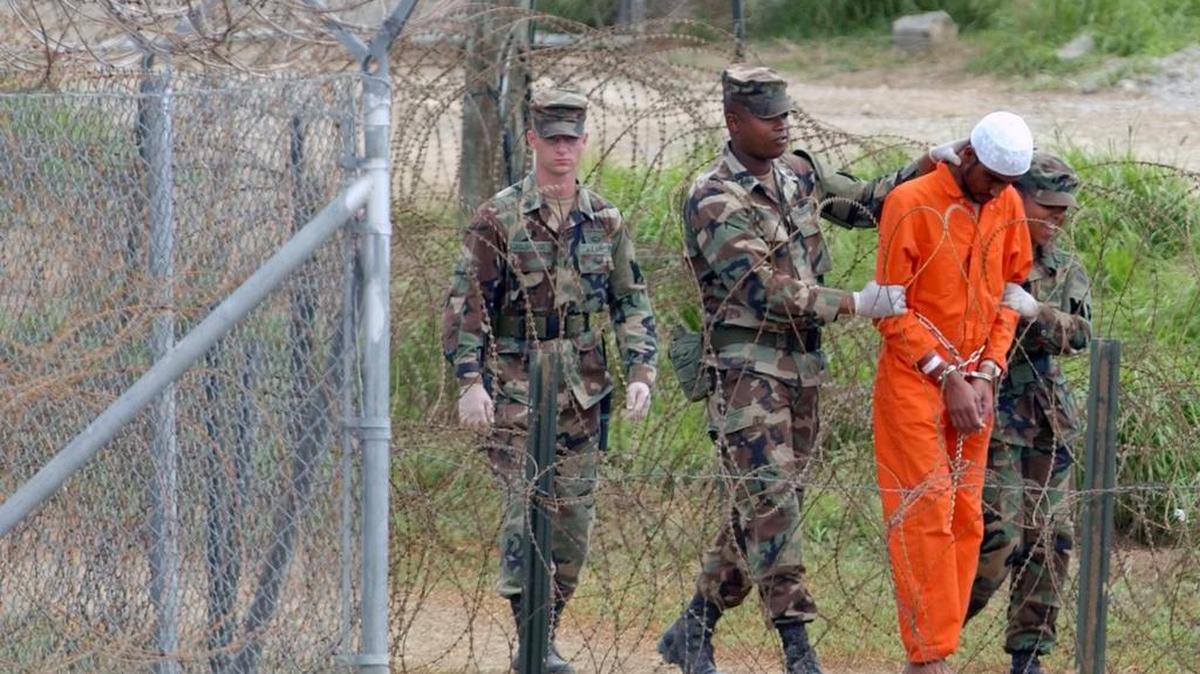 En esta fotografía de archivo del 6 de febrero de 2002, un detenido es conducido por la policía militar para ser interrogado por oficiales militares en el Campamento X-Ray en la Base Naval de Estados Unidos en la Bahía de Guantánamo, Cuba. En el momento en que se tomó la imagen, había 158 prisioneros de al-Qaida y talibanes detenidos en el campo X-Ray. El vigésimo aniversario de la llegada de los primeros presos al centro de detención de la bahía de Guantánamo es el martes 11 de enero de 2022. Ahora quedan 39 presos. En su apogeo, en 2003, el centro de detención tenía casi 680 presos. (Foto AP / Lynne Sladky, archivo)