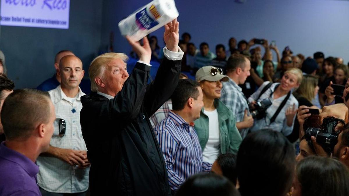El presidente Donald Trump arroja papeles a los asistentes a un evento en iglesia evangélica Calvary Chapel, en Guaynabo, durante su visita a Puerto Rico el 3 de octubre.