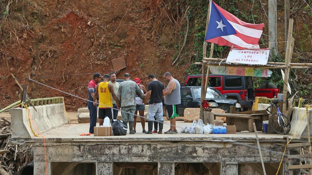 Voluntarios en el pueblo de Isabela se y residentes de Río Abajo se toman las manos para orar en círculo sobre el colapsado puente que le servía de comunicación a los vecinos con el resto de la isla y que la crecida del río destruyó como si fuera de papel.