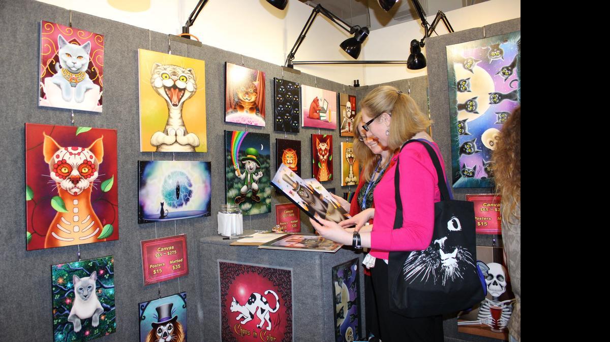 
Una mujer observa cuadros y afiches gatunos exhibidos en la convención CatConLA, dedicada a los gatos, en Los Angeles, California. 
