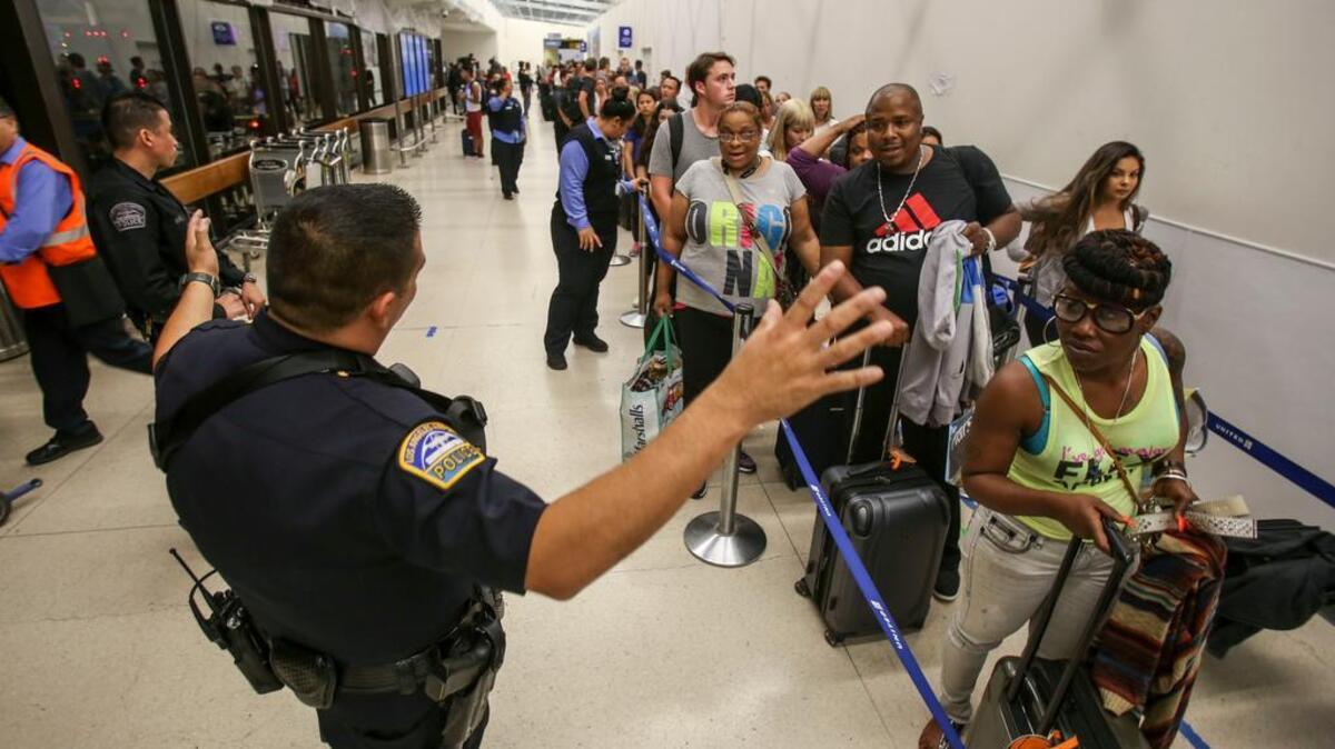 Un policía mantiene el orden en una fila de pasajeros que esperan en la Terminal 7 del Aeropuerto Internacional de Los Ángeles.