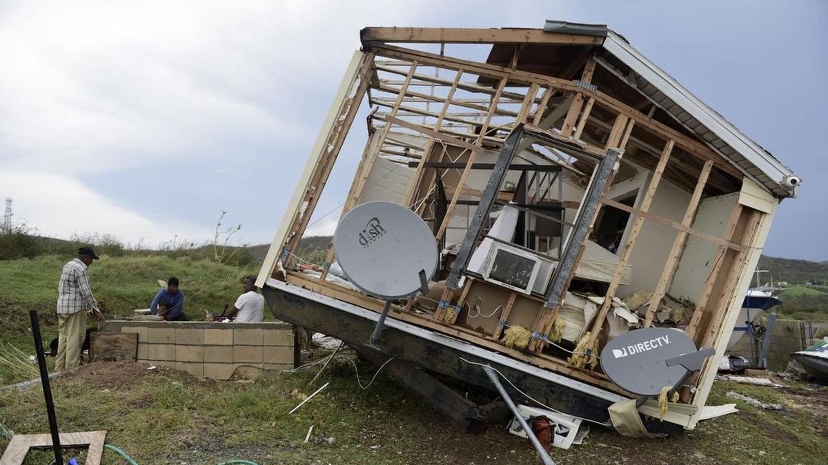 Juan Negrón (der.) se prepara para encender un generador eléctrico frente a lo que queda de su propiedad después del impacto del huracán Irma, el 7 de septiembre de 2017 en la isla de Culebra, Puerto Rico.