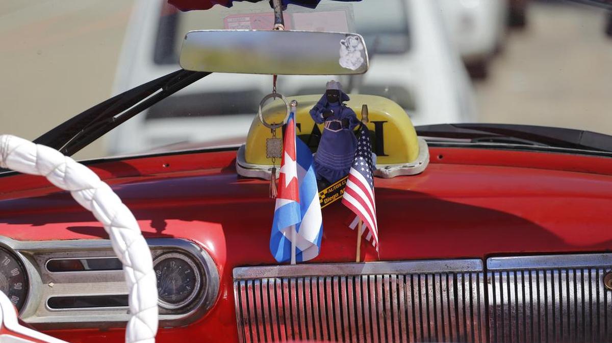 La bandera de Estados Unidos y la de Cuba, en un automóvil antiguo que transita una calle de La Habana, el jueves 18 de febrero.