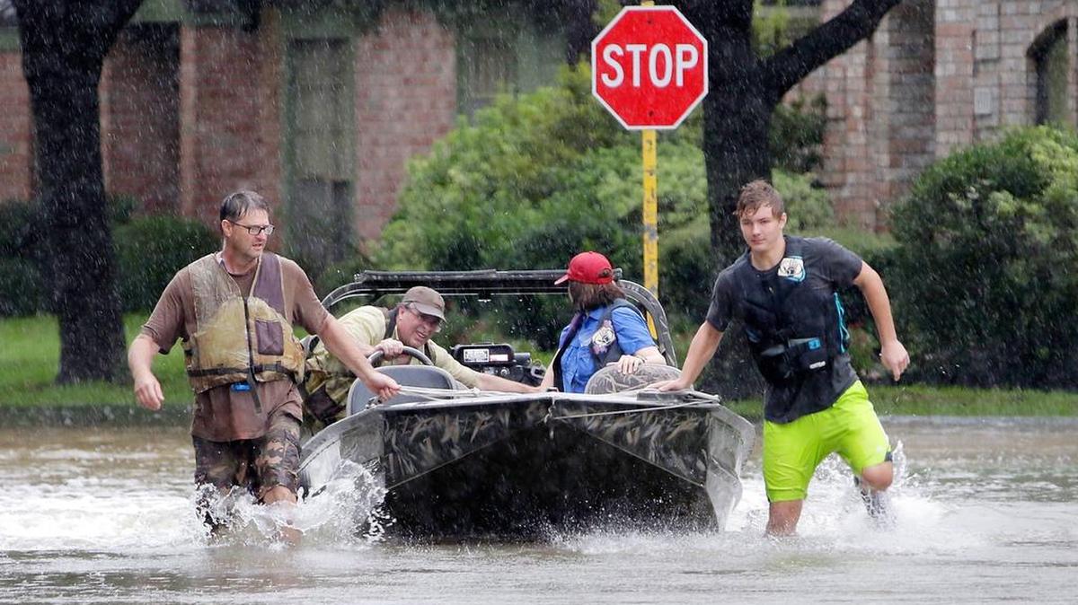 Voluntarios remolcan una barca en busca de residentes atrapados el lunes 28 de agosto de 2017, en Houston