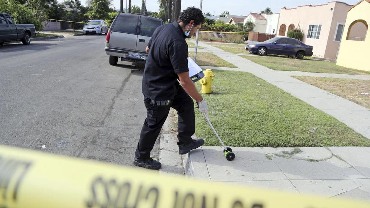 Un agente de la policía de Los Ángeles inspecciona la escena de un tiroteo fatal en el barrio de Crenshaw en Los Ángeles, el sábado 15 de octubre de 2016.