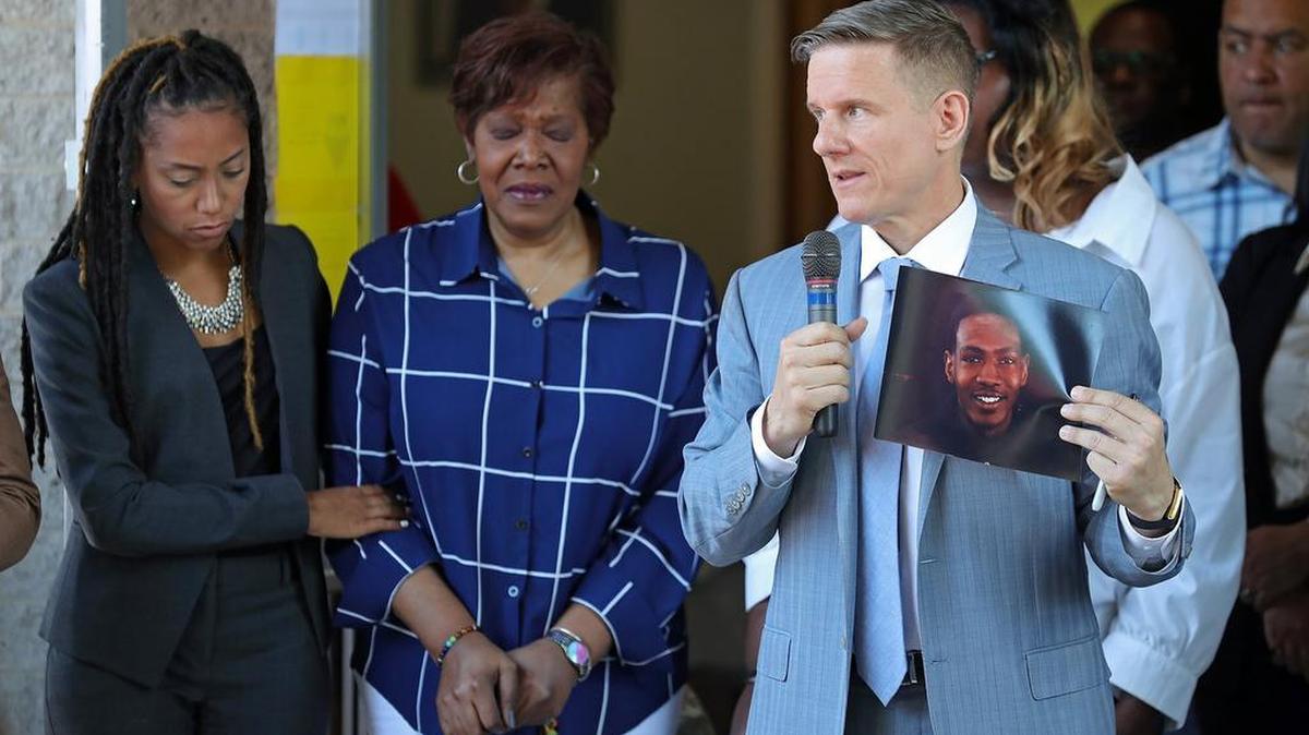 Attorney Bobby DiCello, right, holds up a photograph of Jayland Walker as attorney Paige White, left, comforts Jayland’s mother Pamela Walker during a news conference at St. Ashworth Temple, Thursday, June 30, 2022, in Akron, Ohio. Walkler, shot and killed by police following a vehicle and foot pursuit this week died from multiple gunshot wounds, and his death has been ruled a homicide, authorities announced Wednesday.(Jeff Lange /Akron Beacon Journal via AP)