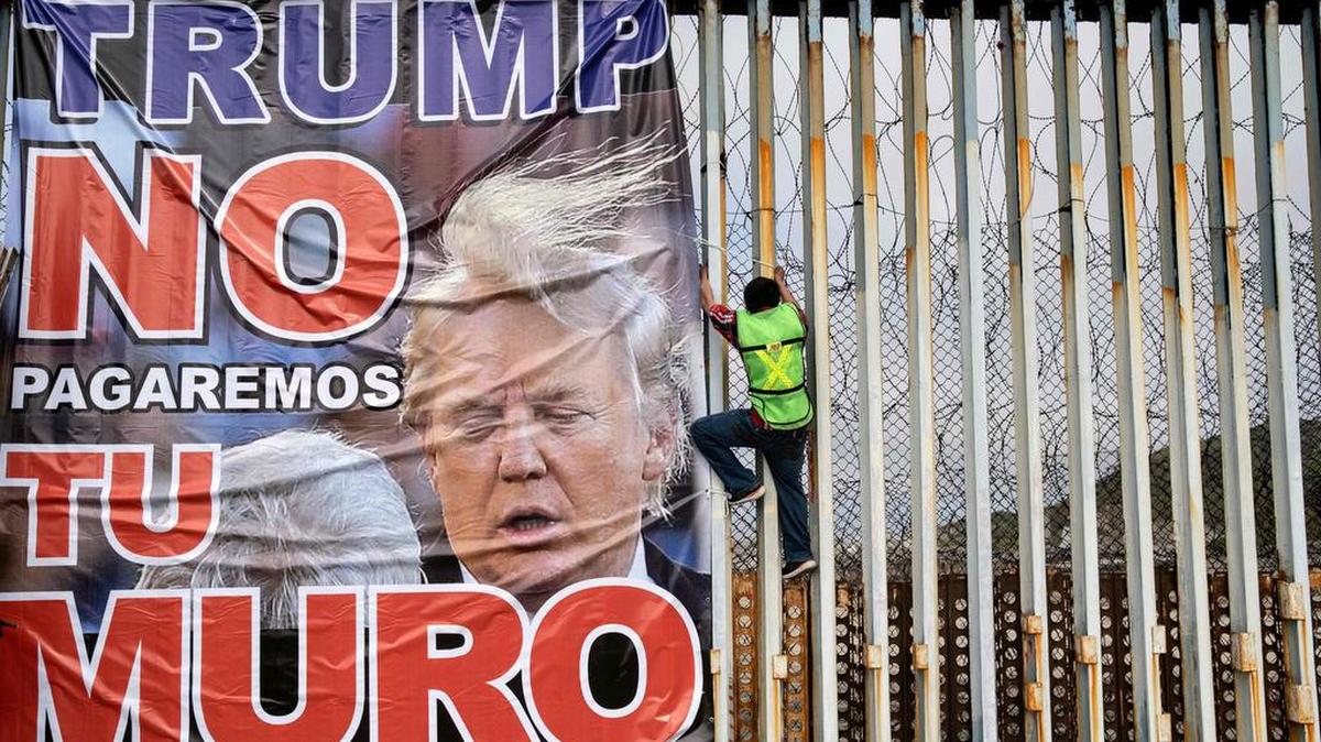 Un hombre cuelga un cartel contra la construcción del muro fronterizo en Playas de Tijuana, Baja California, el 2 de febrero del 2020.