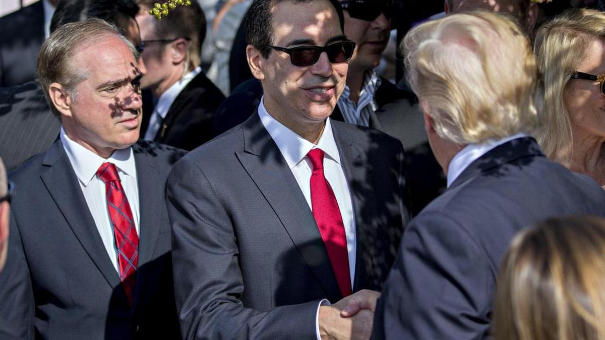El presidente estadounidense, Donald Trump (d), saluda a su secretario del Tesoro, Steven Mnuchin, durante la ceremonia de conmemoración del decimosexto aniversario de los atentados del 11 de septiembre de 2001, en el Pentágono, Arlington, Virginia (Estados Unidos), el 11 de septiembre de 2017.