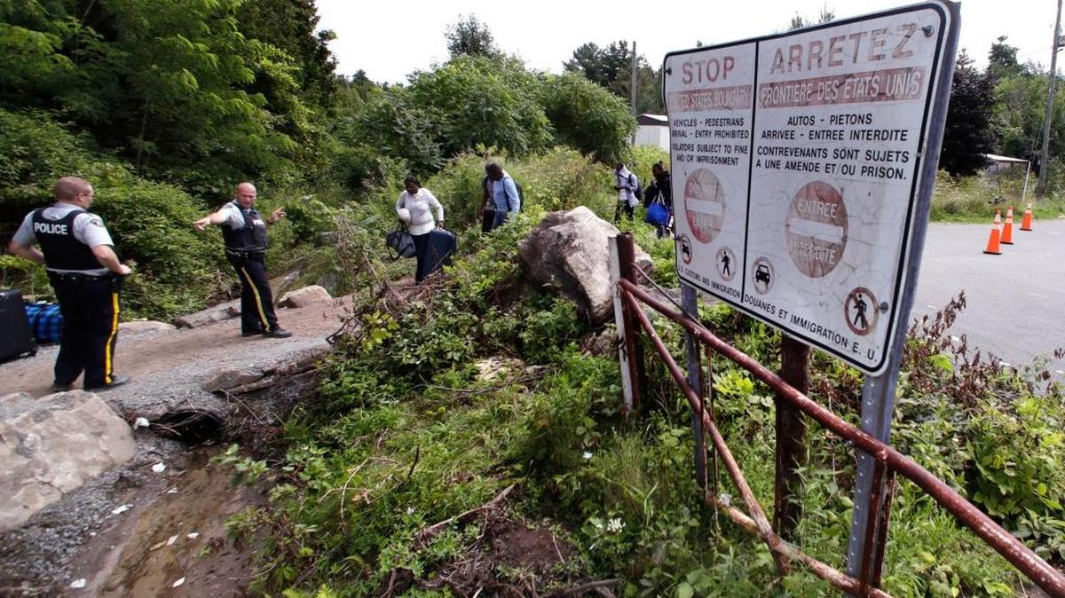 Agentes de la Real Policía Montada de Canadá inofrman a unos inmigrantes que serán arrestados si ingresan a territorio canadiense desde Champlain, Nueva York.
