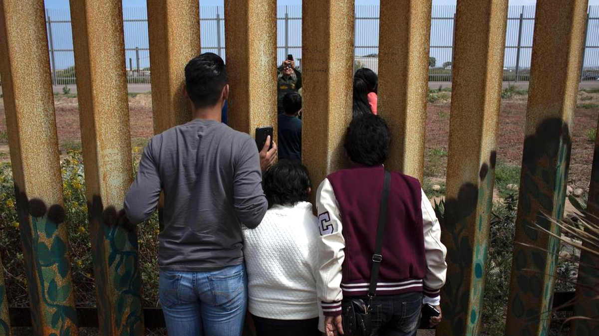 Un agente de la Patrulla Fronteriza de Estados Unidos le toma una fotografía a miembros de la familia Rosete-Quintana, algunos se encuentran en EEUU y otros del lado mexicano del muro, el 2 de julio en las playas de Tijuana, México.