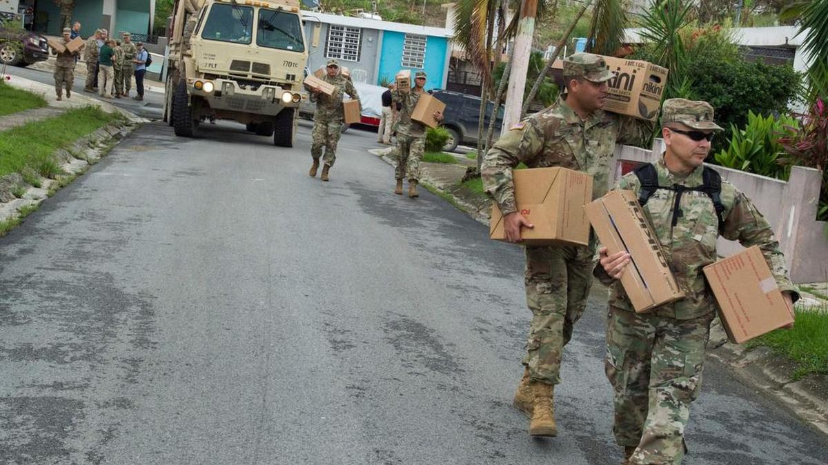 En esta imagen publicada por el Departamento de Defensa de EE UU, soldados entregan casos de agua y comida a los residentes de uno de los barrios más dañados de Jayuya, 11 de octubre de 2017.