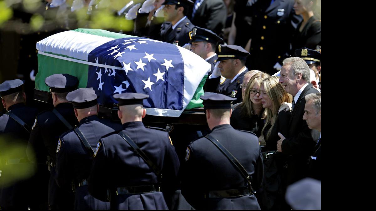 
Policías trasladan el ataúd con los restos mortales del agente Brian Moore en presencia de su padre, Raymond (der.), su hermana, Christine (cen), y su madre, Irene (izq), durante su funeral, en la iglesia católica de S. James, en Seaford, Nueva York, el viernes.
