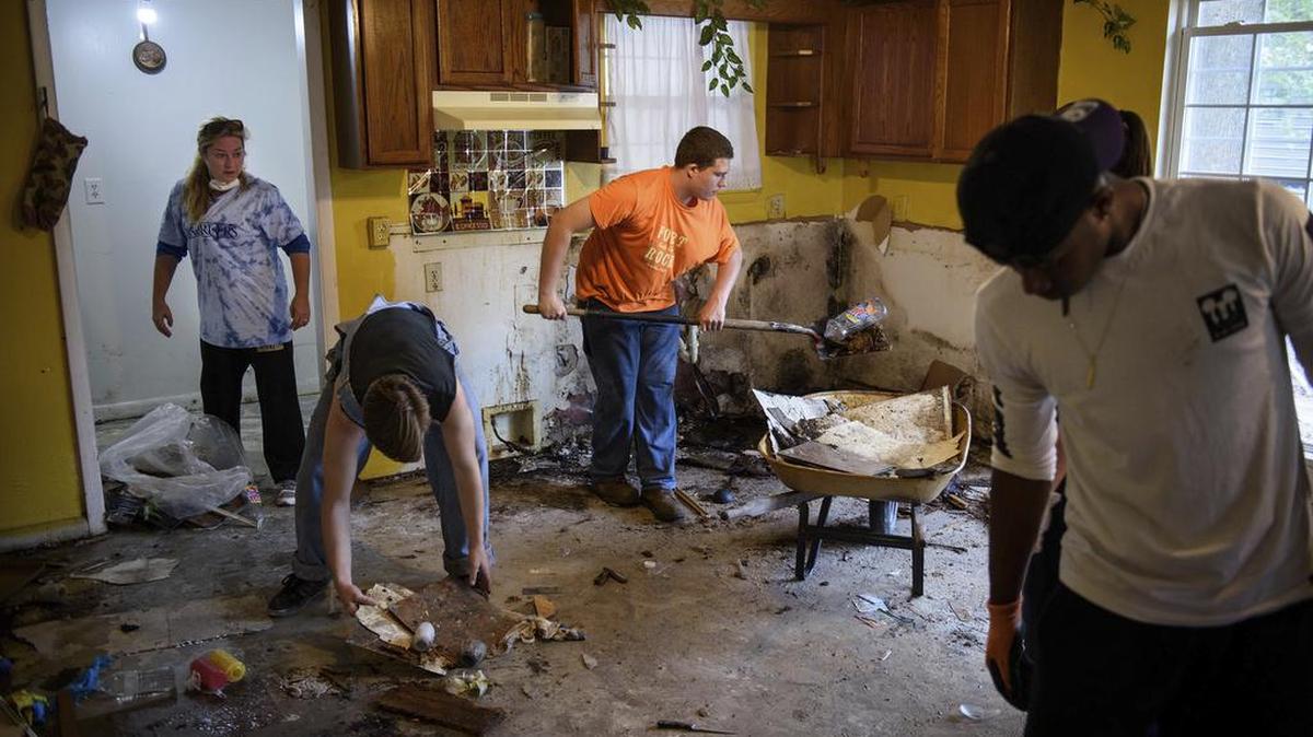 Estudiantes y empleados de la Escuela Cristiana Fayetteville ayudan a limpiar la casa de Chynthia Quick, que fue dañada por las inundaciones, el viernes en Fayetteville, North Carolina.