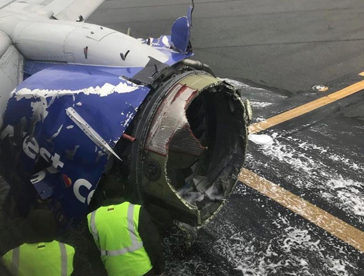 El motor de un avión de Southwest Airlines se inspecciona mientras se encuentra en la pista del aeropuerto internacional de Filadelfia después de aterrizar de emergencia en Filadelfia, el martes 17 de abril de 2018.