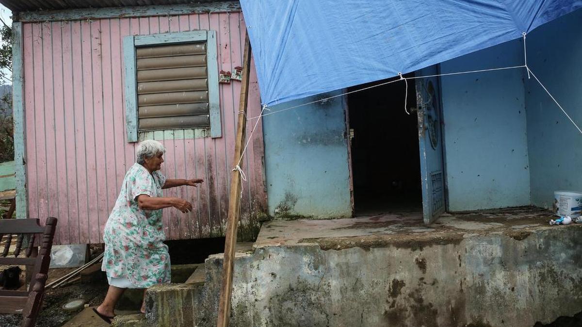 Luz Sota Rivera camina hacia su casa dañada el 12 de octubre de 2017 en Jayuca, Puerto Rico.