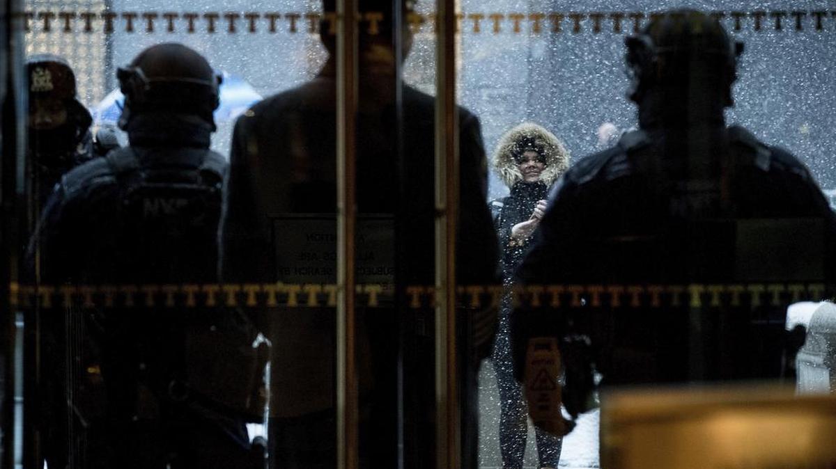 La policía de Nueva York guarda la entrada al Trump Tower mientras los transeúntes toman fotos desde la calle.